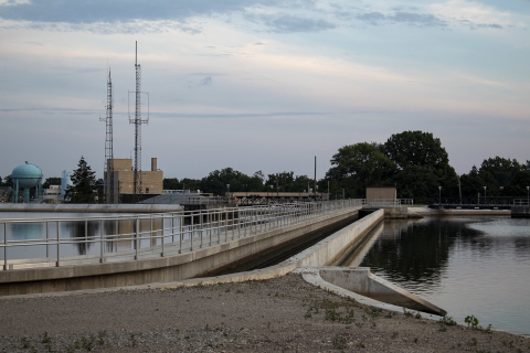 A dam on a calm canal situated in an industrial setting.