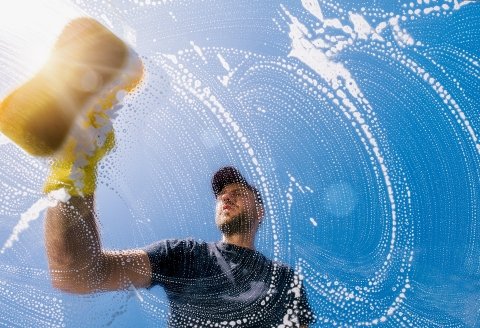 A man cleaning a window with a sponge and soapy water