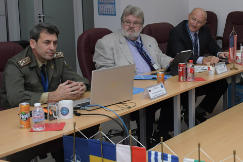 A team from NNSA -- shown here sitting at a table with flags on it -- met with their Bulgarian counterparts to develop a NATO course. 