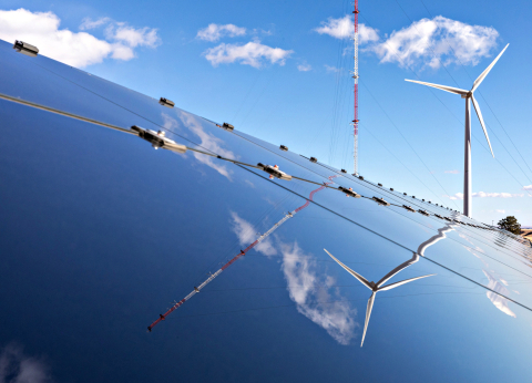 A wind turbine and solar panel on a sunny day.