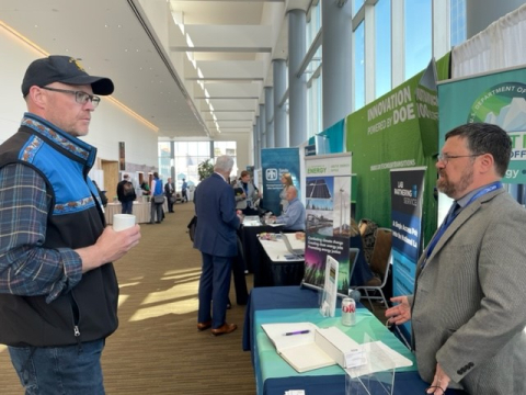 Matt Bergen from Kotzebue Electric stands at left listening to Mike McEleney at the Arctic Energy Office booth.