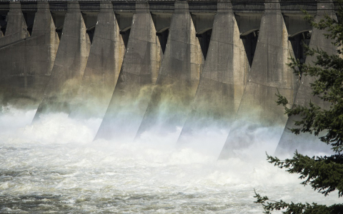 A rainbow above churning water at a hydropower dam