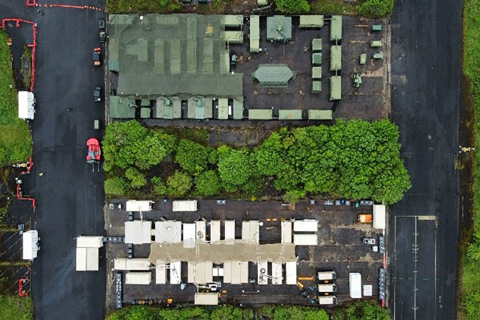 An aerial photo looking straight down at several shipping containers in rows. The top set is green and the bottom set is white.