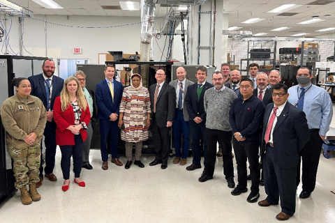 A group of about 18 people pose for a photo in a data center.