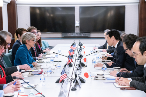 U.S. Secretary of Energy Jennifer Granholm and Minister of Economy, Trade and Industry of Japan Nishimura Yasutoshi look at each other across a table in a conference room with other government officials during a meeting.