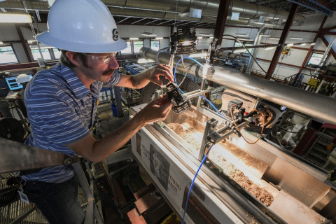 A person wearing a hard hat, installing a light in a lab.