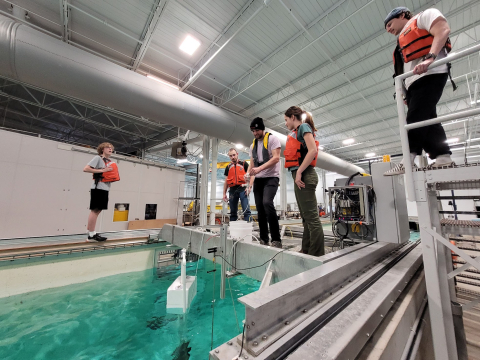 Students wearing life jackets testing marine energy technologies in a small body of water