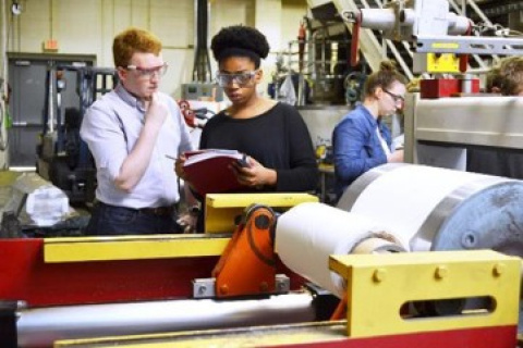 three people working in a manufacturing facility wearing goggles