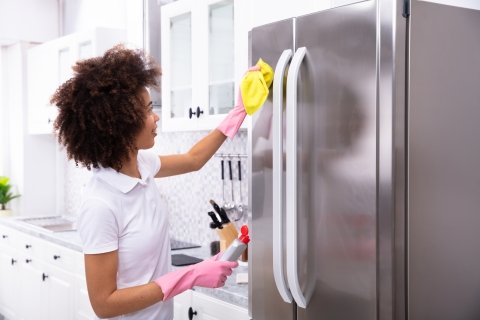 Woman cleaning the front of a refrigerator