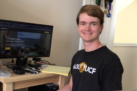 Photograph of Cameron Whitehead at a computer smiling