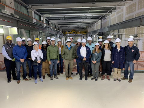 Group of people wearing white hard hats pose for a picture