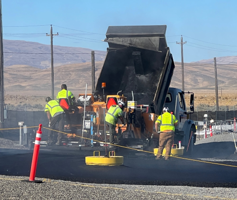 Workers transfer customized asphalt from a delivery truck to construct a surface barrier above U Tank Farm on the Hanford Site.