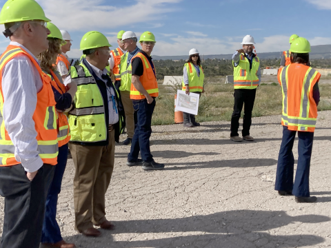 A group of people listening to man as he points and speaks. 