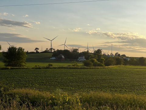 Wind turbines at the back of an open field. 