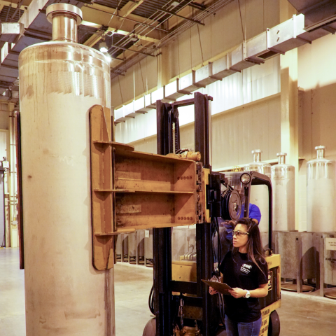 Female employee observes stringent safety standards while moving a 10-foot-tall, stainless steel canister.