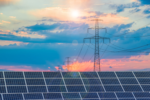 Photo of solar panels against a backdrop of sky and transmission lines