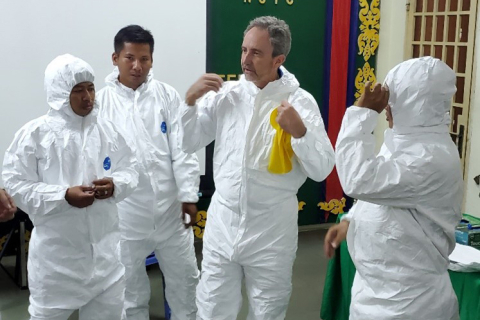 Four men in white, protective suits discussing emergency response.