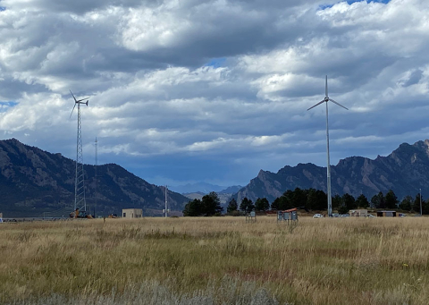 Multiple wind turbines in a filed outlined by mountains. 