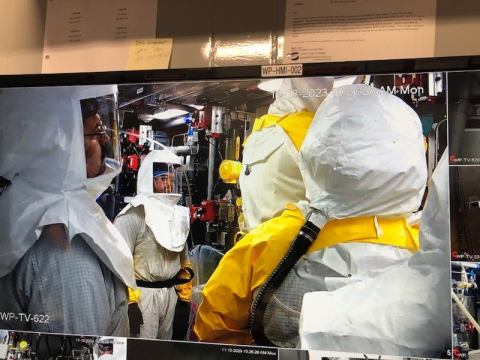 A control room monitor displaying workers performing maintenance 