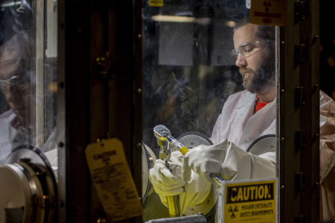 Worker shown using protective gloves to secure a cap onto a cylinder. 