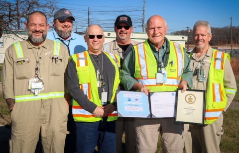 Group of men in safety vests holding award certificates.