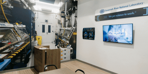 SRNL "storefront" view of room with computer equipment and flat screen TV on wall.