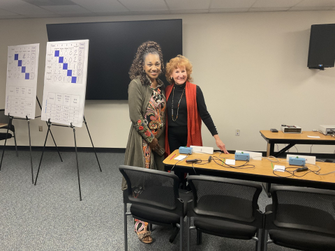 Two women posing for a picture in a classroom