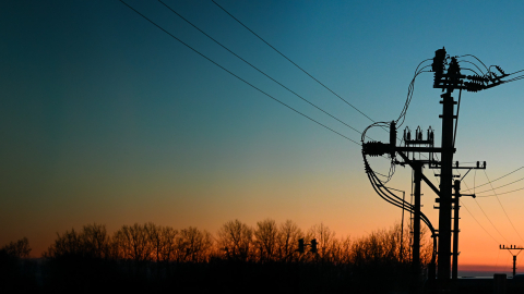 Distribution transformers in a field at sunset. 