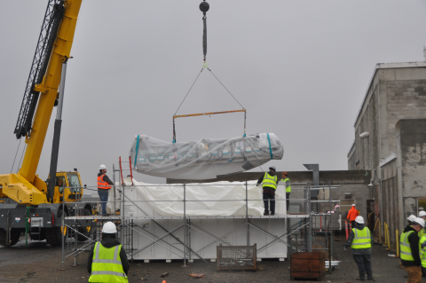 EM Crews using a crane to lower a large glove box into a metal container