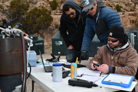 Researchers sit at a table outside while carrying out groundwater sampling