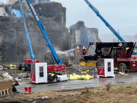 Construction vehicles and equipment with workers demolishing a building