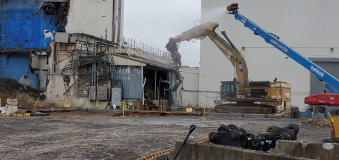 A building being demolished by large equipment machines 