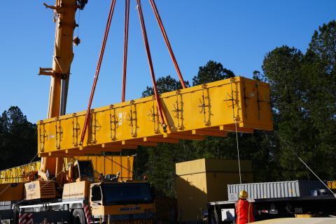 Crane lowering container unto flatbed truck