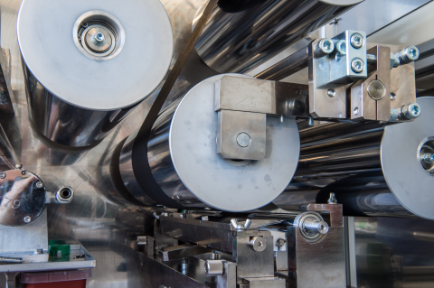 A paper-like material is wound through several metal rolls