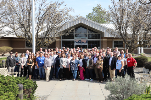 A large group of people pose for a picture outside in front of a building