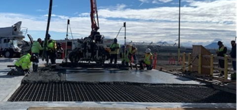A construction site with lots of employees in safety gear and construction vehicles