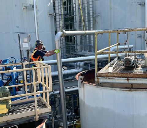 An employee standing on a raised ledge while installing piping