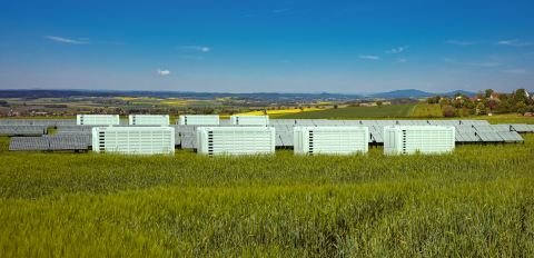 White energy storage containers in a field during daylight hours. 