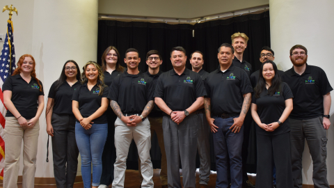 A group of young men and women in black polo shirts pose for a photo