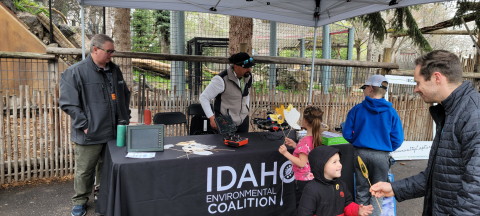Employees running a booth at a zoo event talk to children and parents