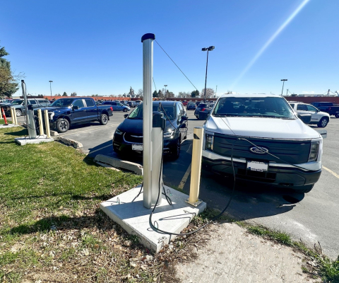 Two vehicles parked in a parking lot plugged up the electric vehicle chargers