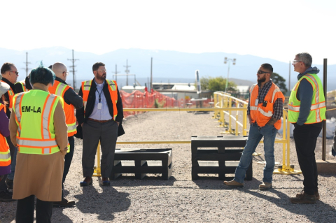 Workers in neon yellow and orange safety vests stands at a construction site