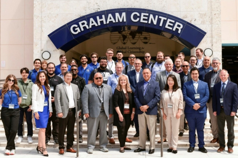 A large group of people pose for a picture in front of a building with the words Graham Center on it