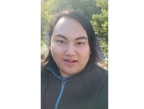 Selfie of Andrew Tong standing outside with greenery in the background