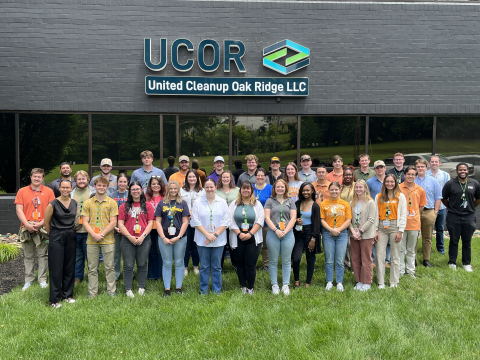 A large group of people stand outside a building and pose for a group photo