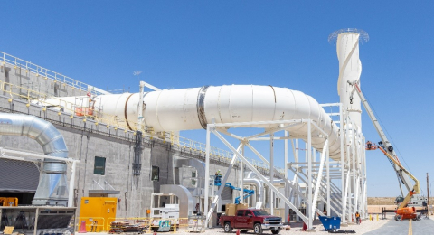 A large factory building with large, white ductwork coming out of it and beside it