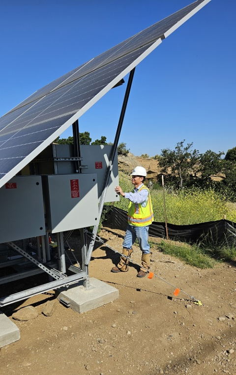 A person stands behind a solar skid panel.