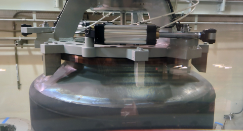 A black cylinder machine being held by a metal structure 