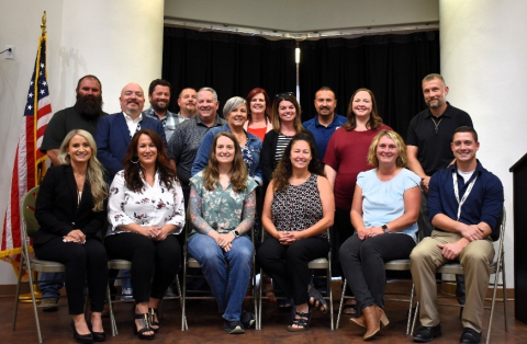 A group of individuals pose for a group picture, some people stand while others sit