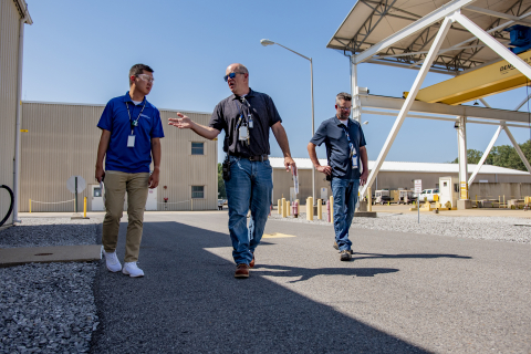 3 men walking outside of facility buildings